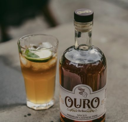 A bottle of Ouro De Goa spiced cashew feni next to a feni cocktail